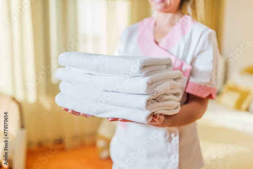 Close up image of hotel maid holding fresh and clean towels.	