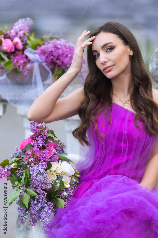 Fashion Model in Lilac Flowers, Young Woman in Beautiful Long Dress Waving on Wind, Outdoor Beauty Portrait in Blooming Garden Fashion Model in Lilac Flowers, Young Woman in Beautiful Long Dress Waving on Wind, Outdoor Beauty Portrait in Blooming Garden