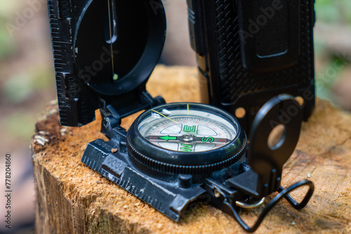 Old compass with handy talkie on a log, in the forest. direction finder compass. concept of hunting in the forest photo