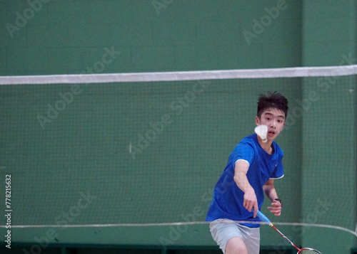A teen boy plays a badminton tournament