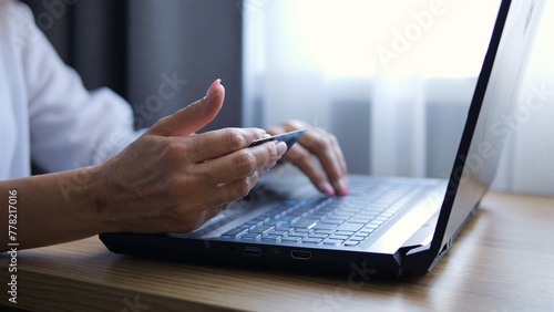 Woman makes online purchases seamlessly using her bank card. Shopping cart fills with items as bank card details are entered. With each transaction her bank card securely facilitates purchase process