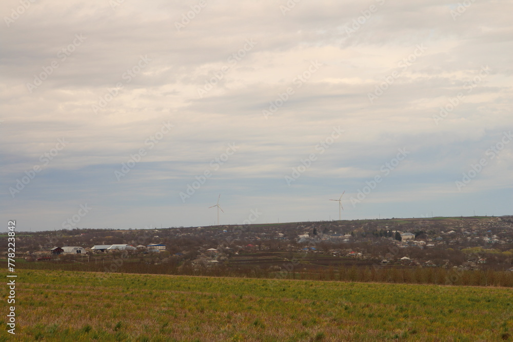 A landscape with a large field and a few houses in the distance