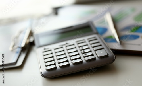 Silver calculator with gray keyboard is lying on desk graph and pen office setting. Calculation of family expenses social income population freelance irs situation growth research concept photo