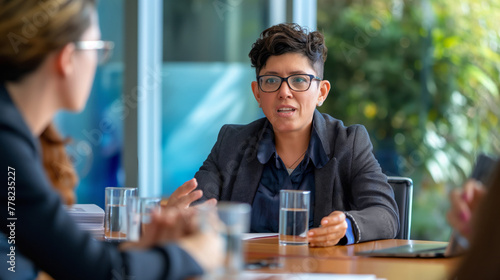 Non-binary executive leading an inclusive corporate meeting discussion on gender diversity and equality in the workplace with a diverse team of professional leaders. Emphasizing open communication photo