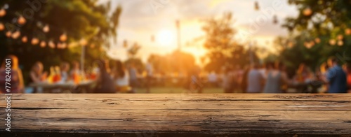 A group of people are gathered around a wooden table, enjoying a sunny day. The atmosphere is lively and social, with people chatting and laughing. The table is set with plates, cups, and utensils