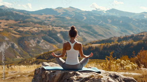 female young girl doing yoga lotus pose meditating on rock with beautiful natural mountains view