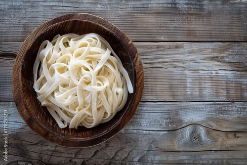 A wooden bowl filled with pasta resting on a wooden table