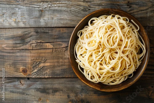 A bowl filled with spaghetti noodles sits on a wooden table