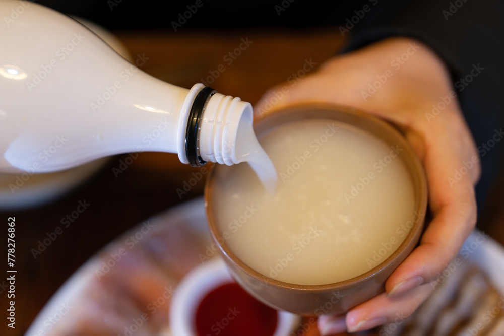pouring makgeolli, Korean rice wine into the cup