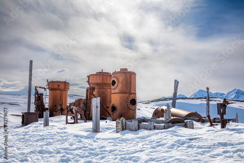 Abandoned marble mining machinery at Camp Mansfield, New London, Svalbard. Snow covered mountain background with blue sky.