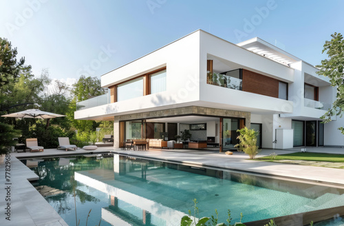 Modern house with pool in Dubai, featuring white walls and wood accents. The exterior includes large windows overlooking the swimming area, surrounded by lush greenery © Kien
