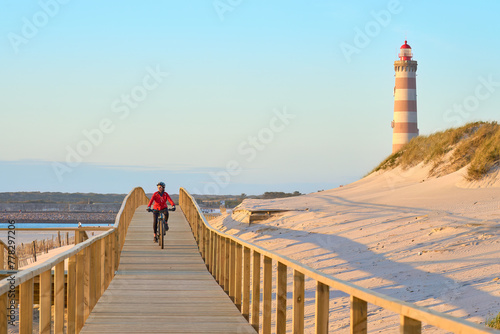 Fotografía happy active senior woman cycling during moody golden hour at the beach of the a