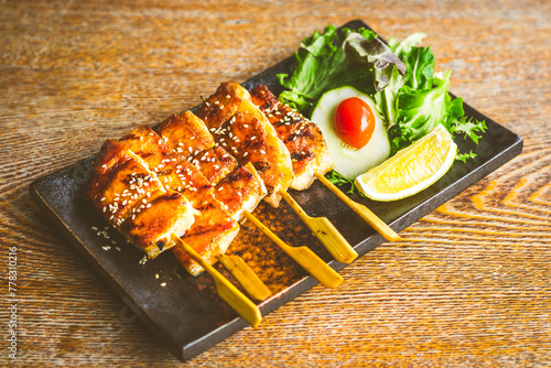 grilled salmon belly skewer with teriyaki sauce and sesame seeds with salad on the side
