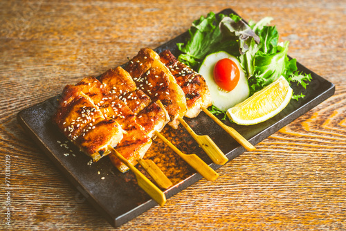 grilled salmon belly skewer with teriyaki sauce and sesame seeds with salad on the side