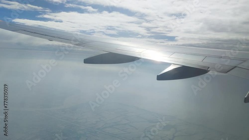 The view from the airplane window. Flying above the blue sky with moving clouds. Traveling on airplane at clear weather day.