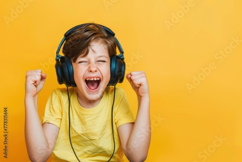 Happy child boy in headphone streamer playing video game with winner expression solid color background photo
