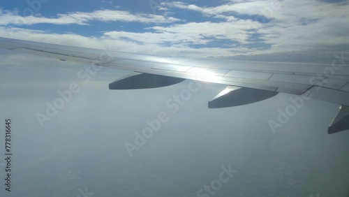 The view from the airplane window. Flying above the blue sky with moving clouds. Traveling on airplane at clear weather day.