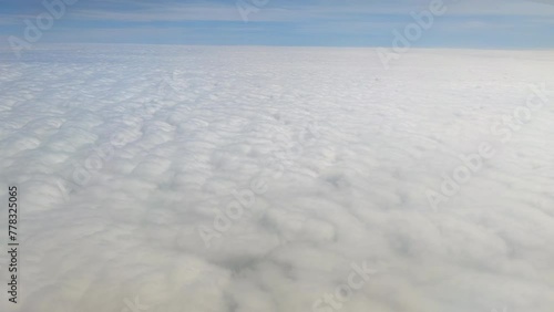 The view from the airplane window. Flying above the blue sky with moving clouds. Traveling on airplane at clear weather day.