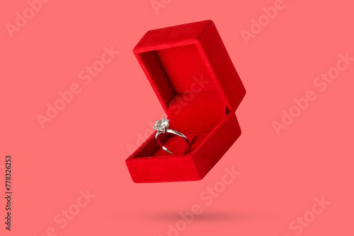 Diamond ring in jewelry gift box floated on red background