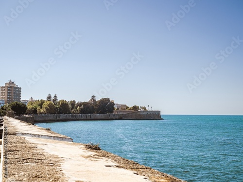 City walls with the bastion Baluarte de la Candelaria and the park of Alameda Apodaca in the Old Town of Cadiz, Spain photo