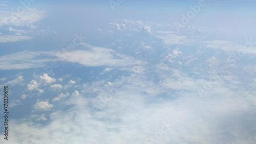 The view from the airplane window. Flying above the blue sky with moving clouds. Traveling on airplane at clear weather day.