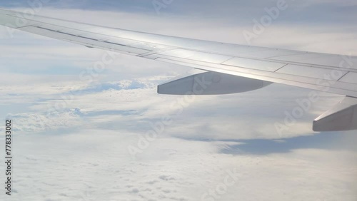 The view from the airplane window. Flying above the blue sky with moving clouds. Traveling on airplane at clear weather day.