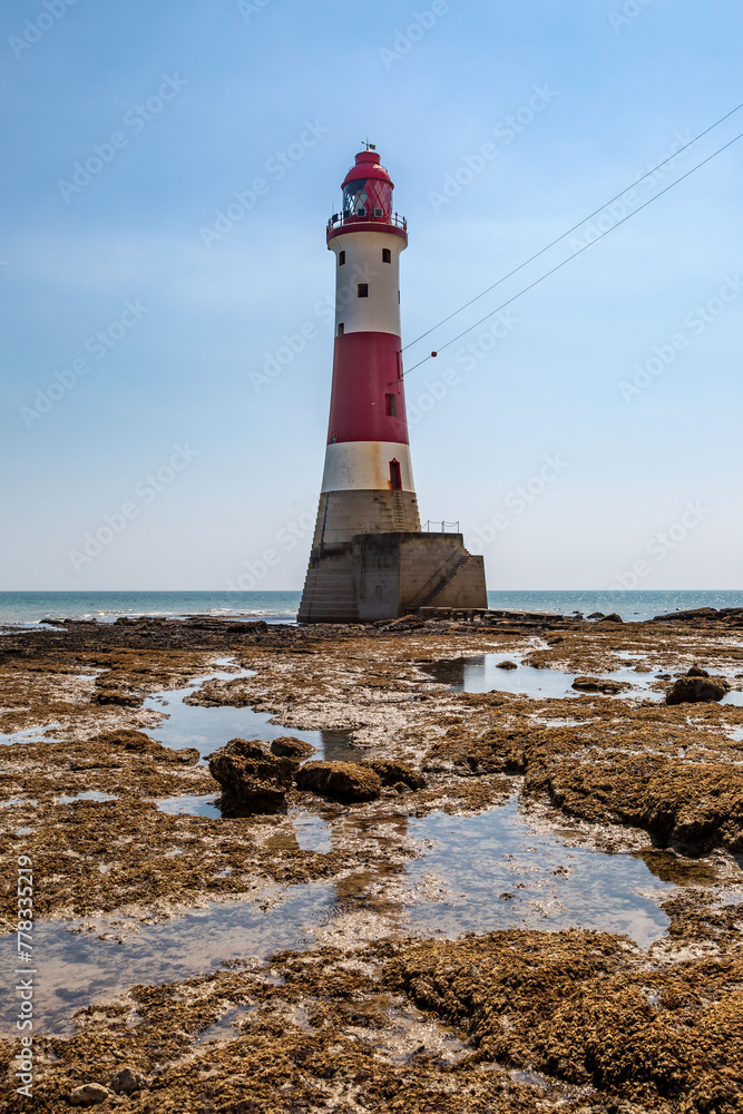 Low tide on the beach at Beachy Head, with the lighthouse against a blue sky