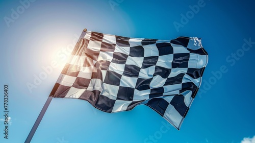 Checkered flag waves against a sunny sky photo