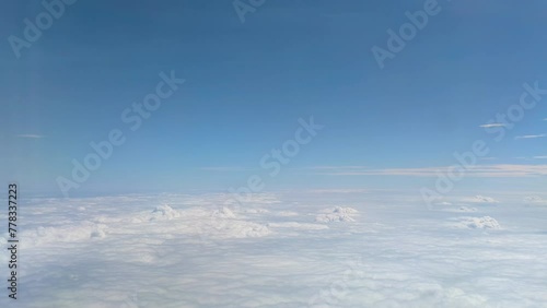 The view from the airplane window. Flying above the blue sky with moving clouds. Traveling on airplane at clear weather day.