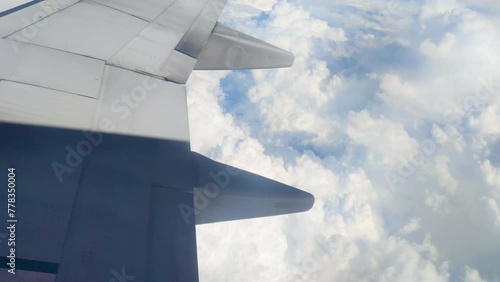 The view from the airplane window. Flying above the blue sky with moving clouds. Traveling on airplane at clear weather day.