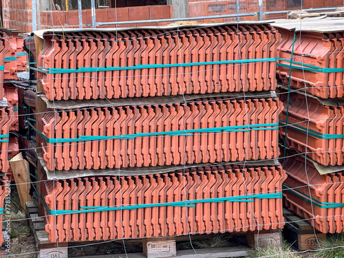 Roof tiles stacked on a pallet, visible from the side as a background