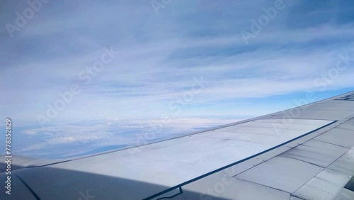 Time lapse The view from the airplane window. Flying above the blue sky with moving clouds. Traveling on airplane at clear weather day.