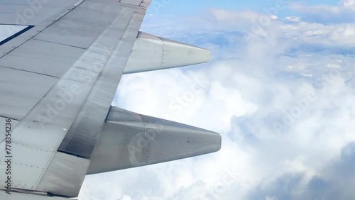 The view from the airplane window. Flying above the blue sky with moving clouds. Traveling on airplane at clear weather day.
