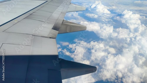 The view from the airplane window. Flying above the blue sky with moving clouds.