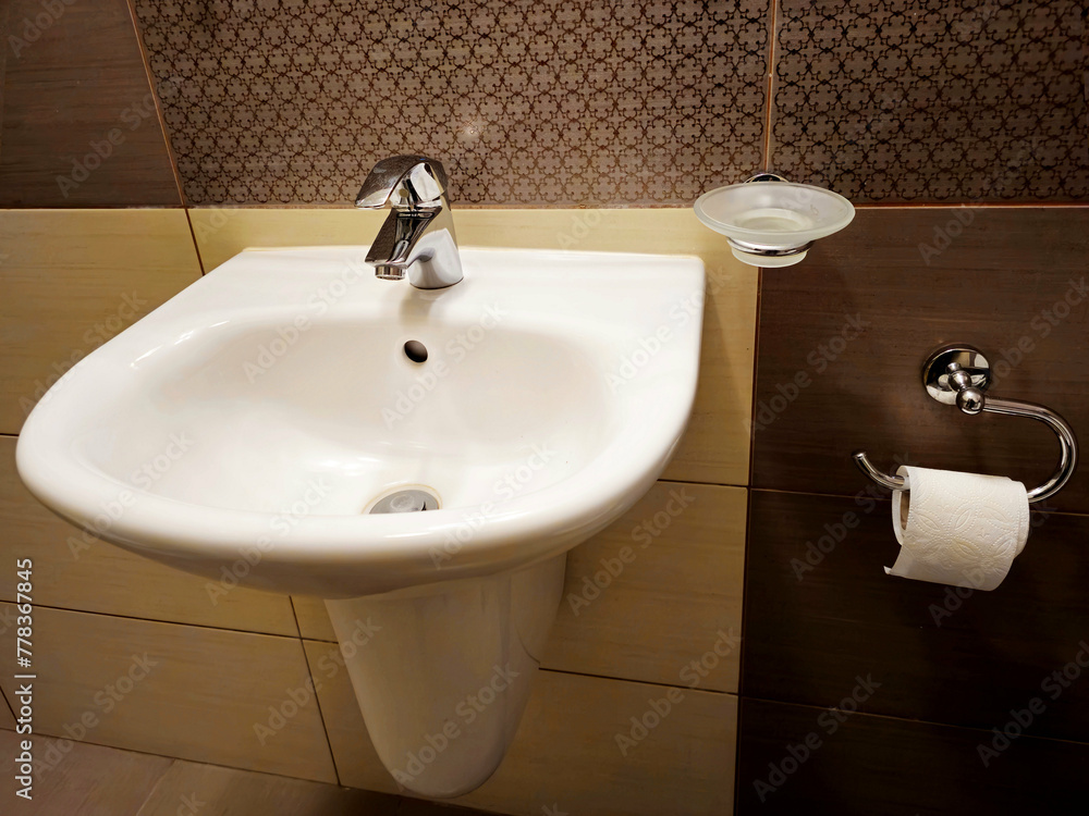 Fototapeta premium The bathroom interior is lined with white ceramic tiles. Oval ceramic urinal. Public place for coping needs. Ceramic household product. Saving running water in everyday life. Restroom Design Solution
