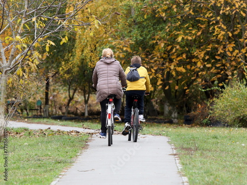 Mom and son ride bicycles along the alley of an autumn park. Healthy and active lifestyle in raising the younger generation. Active recreation in nature. Traveling on two wheels