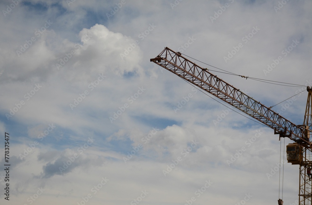 A crane operator comes down after working on a construction crane in the distance. Sky in the clouds A crane operator comes down after working on a construction crane in the distance. Sky in the clouds