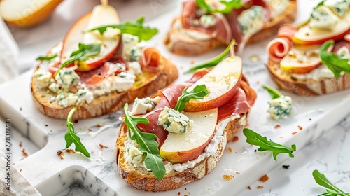 Delicious appetizer crostini, tapas, or open-faced sandwiches featuring pear, prosciutto, arugula, and blue cheese, elegantly arranged on a white marble board. T