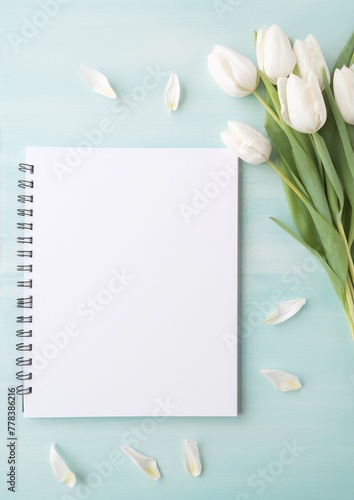 White tulips and petals on a blue wooden background with a blank notebook. Still life, floral, art, photography, interior, blue, white, spring. #778386216