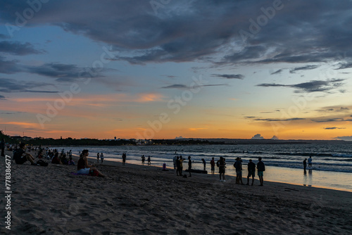 Bali, Indonesia - March 4 2020. silhouettes of tourists enjoying the beautiful sunset at Kuta beach.
