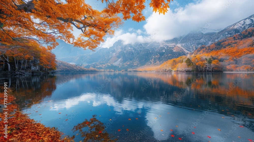 Autumn leaves reflect on a serene lake with a mountain backdrop