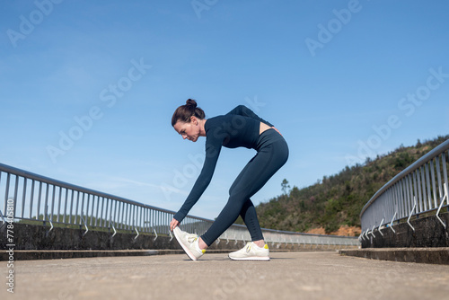 female runner doing warm up leg stretching exercises outside