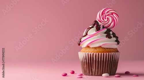 Close-up muffin decoration with white cream and pink lollipop on a pink background, a birthday concept. photo