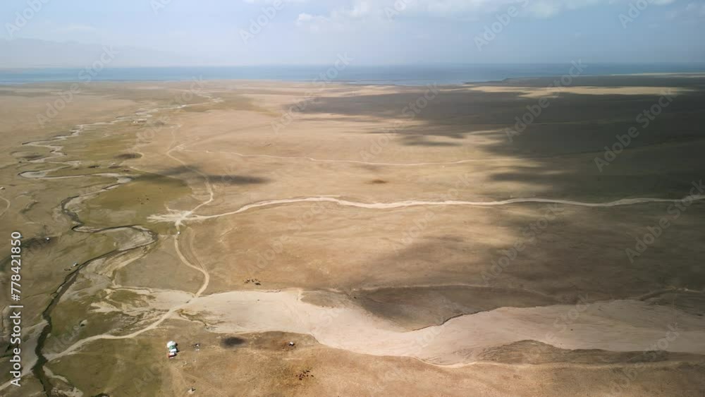 Song-Köl Lake, Kyrgystan. Fixed aerial drone view of nomadic Kyrgyz camps and cow herds in mountain steppes of Central Asia. Cinematic travelling shot of popular adventure tourist destination. Song-Köl Lake, Kyrgystan. Fixed aerial drone view of nomadic Kyrgyz camps and cow herds in mountain steppes of Central Asia. Cinematic travelling shot of popular adventure tourist destination.