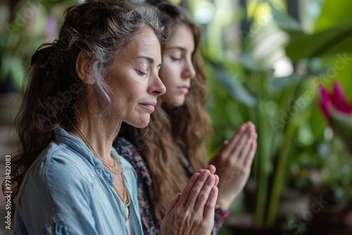 Two women in a sitting position in front of a potted plant, engaging in prayer, A mother and daughter engaged in prayer, AI Generated