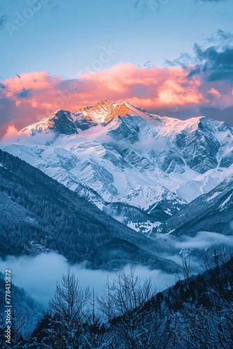 a snowy mountain with clouds and trees photo
