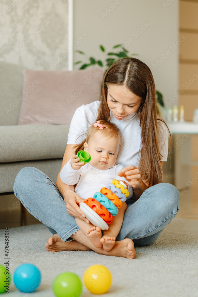 Vertical shot of a young mother playing together with her sweet daughter at home. Vertical shot of a young mother playing together with her sweet daughter at home.