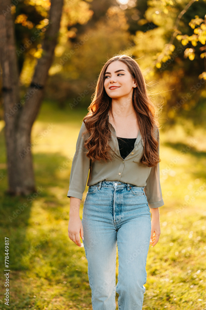 Vertical outdoors shot of a young smiling woman walking in park on a sunny day. Vertical outdoors shot of a young smiling woman walking in park on a sunny day.