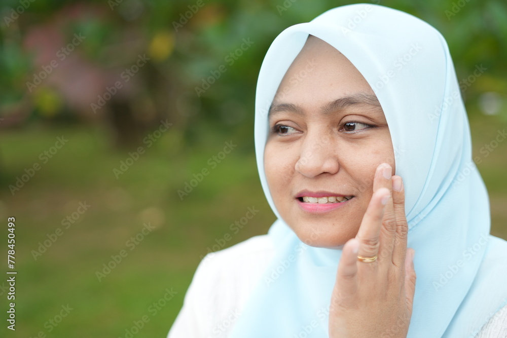 Portrait of an Asian female model wearing a blue hijab with various attractive facial expressions while out in nature during the day Portrait of an Asian female model wearing a blue hijab with various attractive facial expressions while out in nature during the day
