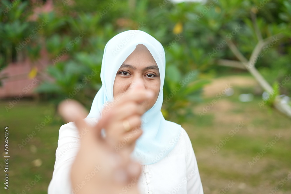 Portrait of Asian female model wearing blue hijab making love symbol with fingers Portrait of Asian female model wearing blue hijab making love symbol with fingers